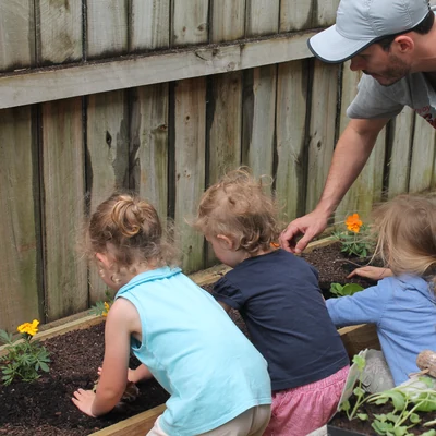 Planting marigolds into the raised bed with the girls, everyone's hands in the soil