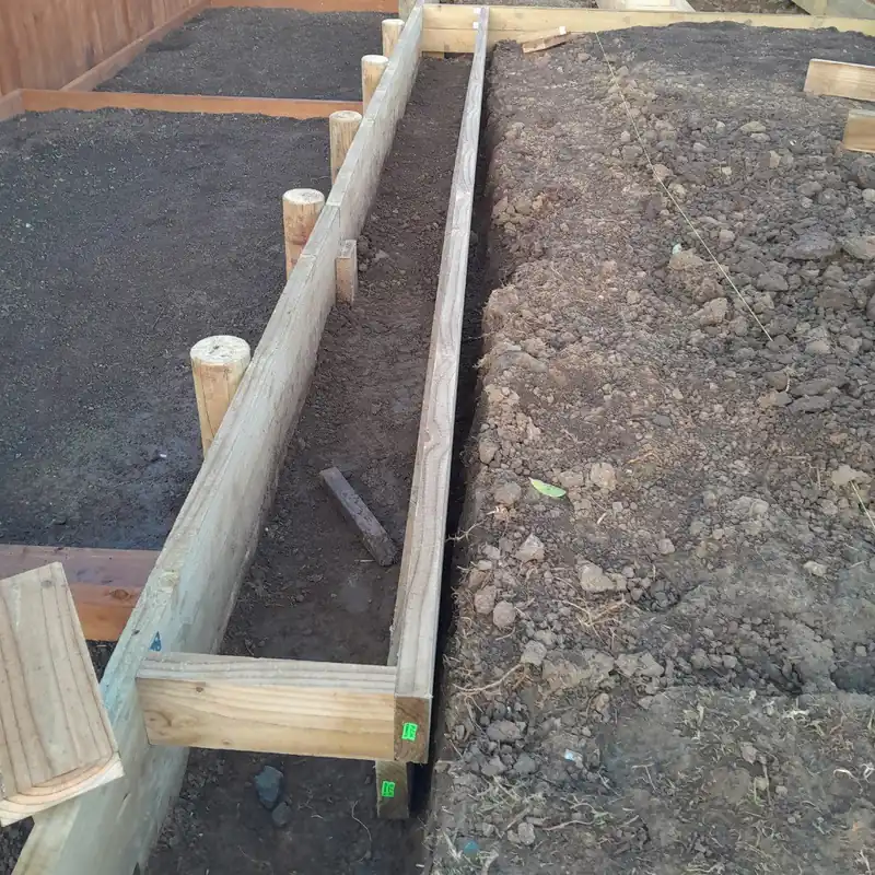 The old ground opened up: worked dark soil on the left, cloddy orange clay on the right, with new timber edging laid between them