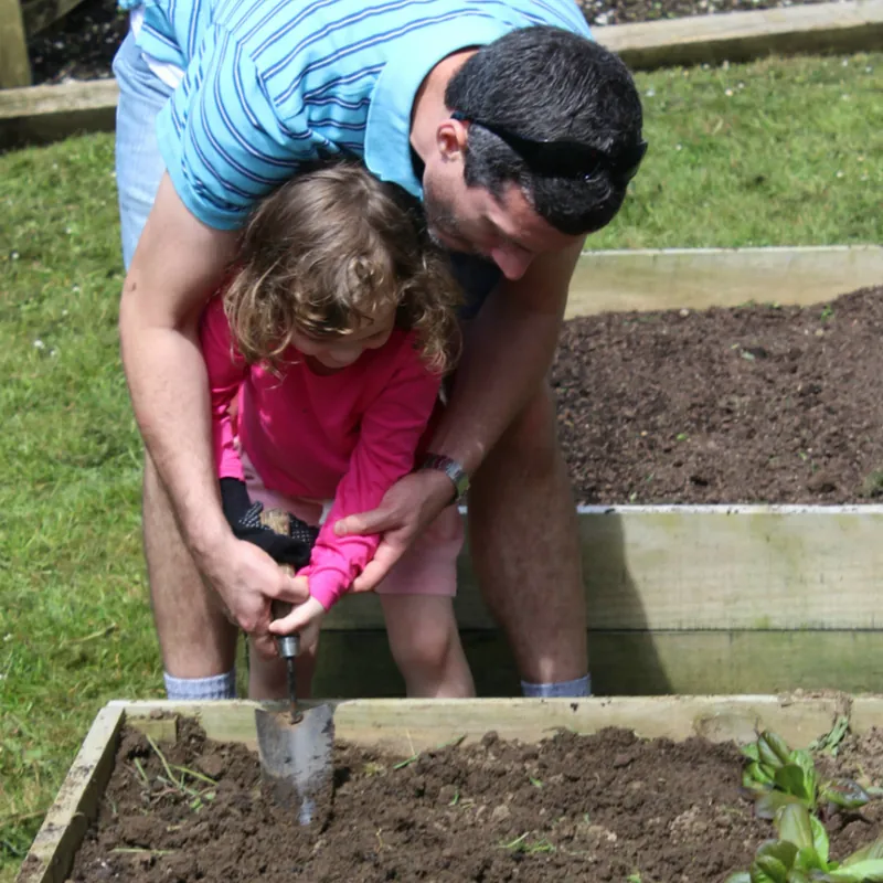 Crouched over the raised bed with the youngest, both our hands on the trowel, planting a seedling