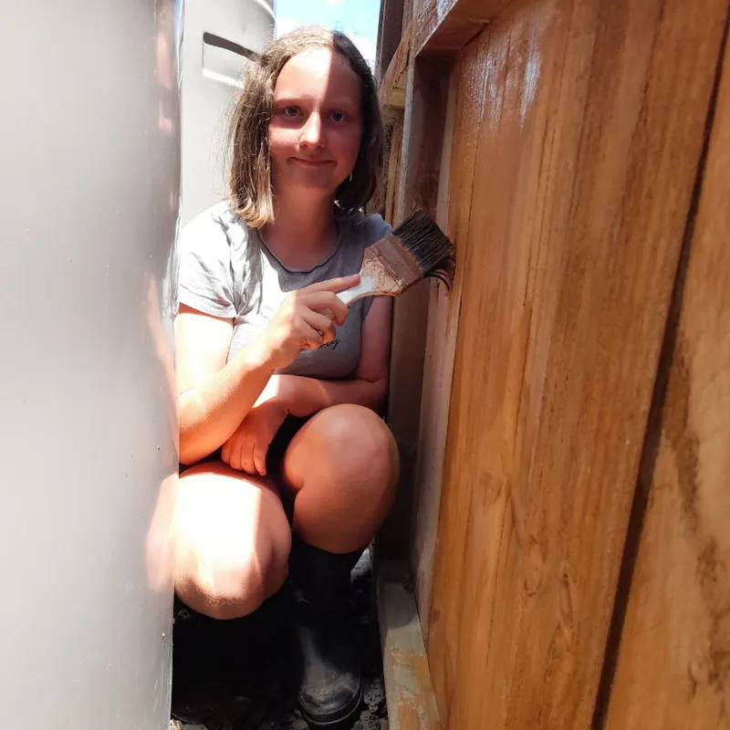 One of the girls crouched in the narrow gap between the water tank and the fence, staining the palings